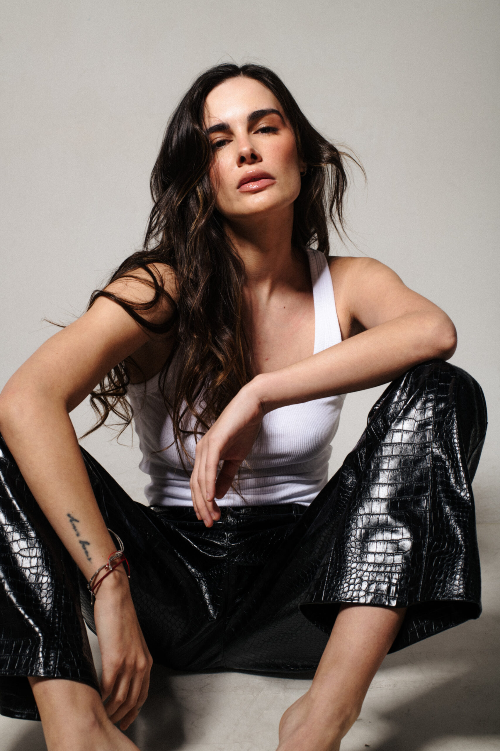 Fernanda de la Vega sentada con top blanco y pantalón negro en estudio